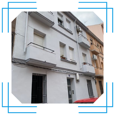 Un edificio blanco con un coche rojo aparcado delante.