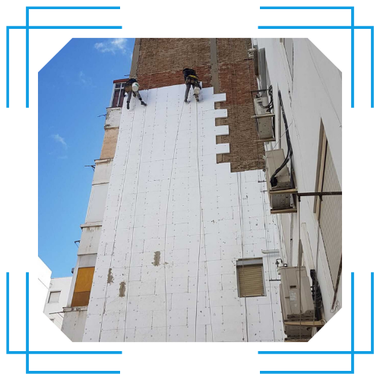 Dos hombres están trabajando en el costado de un edificio.