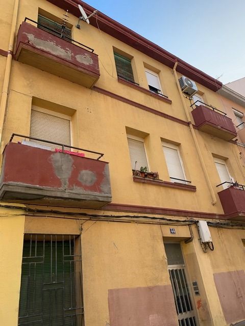 Un edificio amarillo con balcones y persianas rojas