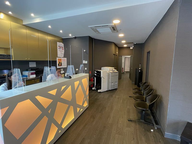 Intérieur d'un café moderne avec un comptoir éclairé, des chaises et un couloir menant à l'arrière.
