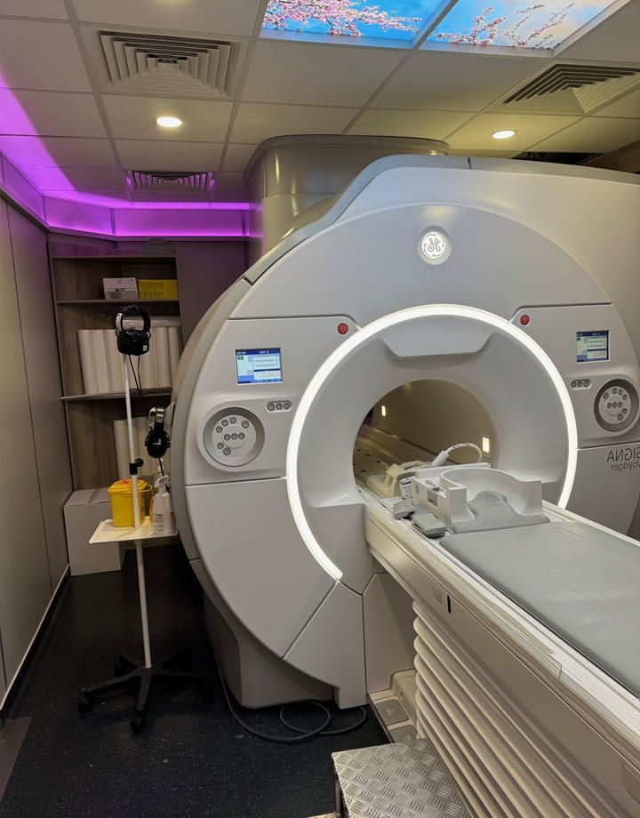 Un appareil d'IRM dans une chambre d'hôpital avec une table d'examen et un éclairage violet au plafond.