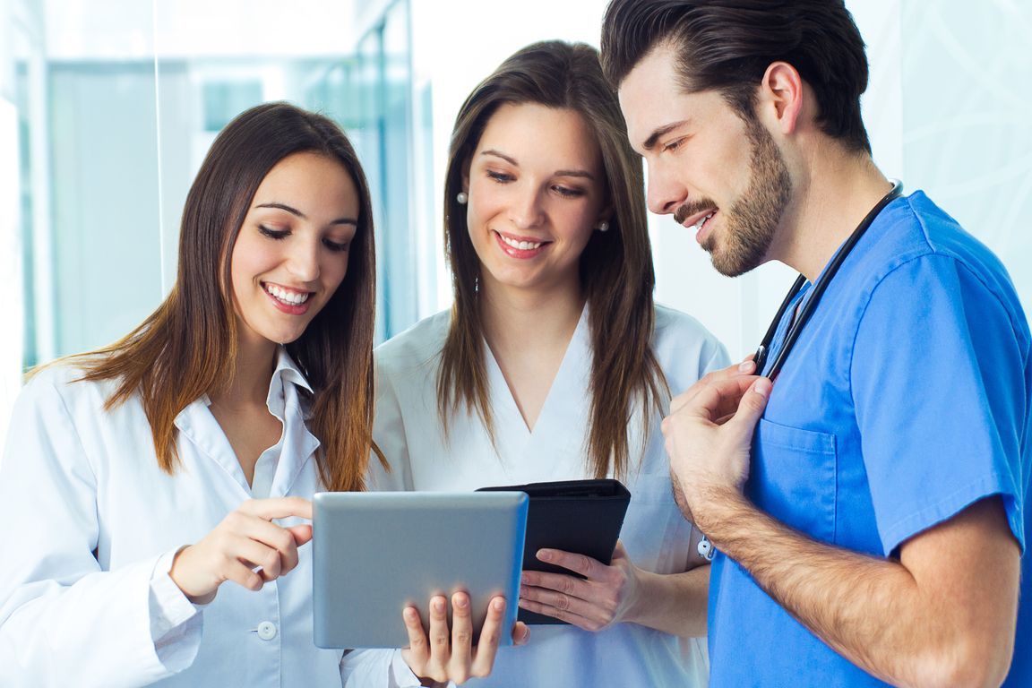 Trois professionnels de la santé examinent ensemble une tablette dans un cabinet médical lumineux.
