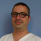 Portrait d'un homme portant des lunettes et une chemise blanche sur fond bleu