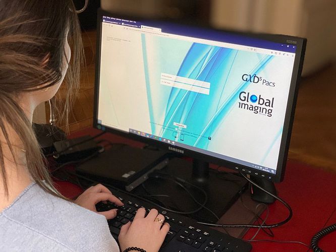 Une personne tapant sur un ordinateur de bureau affiche une page Web de Global Imaging