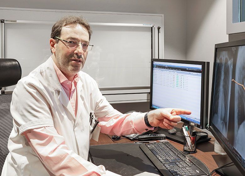 Un médecin en blouse blanche désigne un écran d'ordinateur dans un cabinet médical.