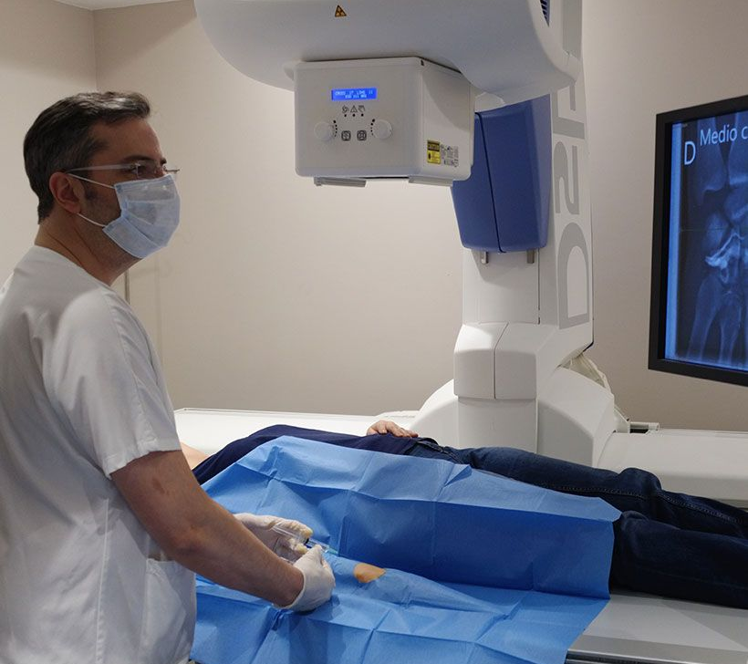 Un clinicien manipule un appareil d'imagerie médicale à côté d'un patient allongé sur une table recouverte.