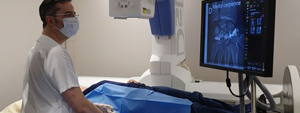Technicien masqué surveillant un examen médical sur un écran d'imagerie hospitalière