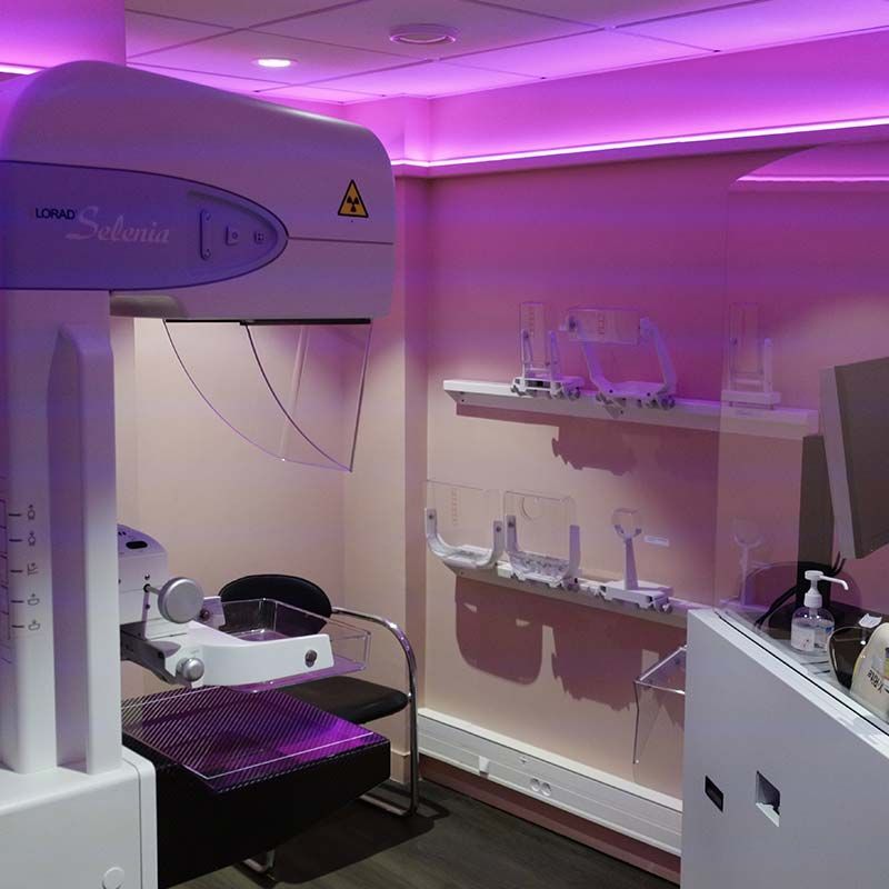 Salle d'imagerie médicale moderne avec table d'examen, équipements muraux et éclairage d'ambiance violet