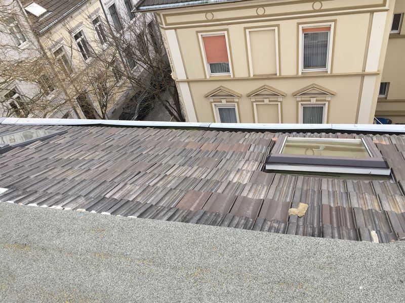 Ein Dach mit einem Oberlicht darauf und einem Gebäude im Hintergrund