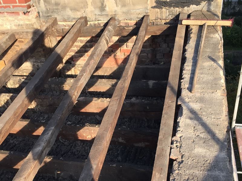 Ein Holzbalken liegt auf einer Betonwand.