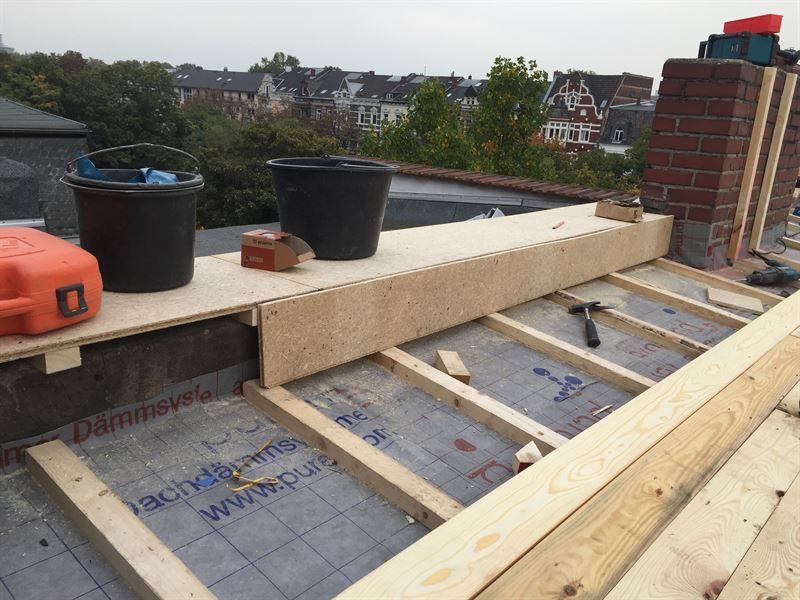 Auf einem Dach wird eine Holzkonstruktion errichtet.