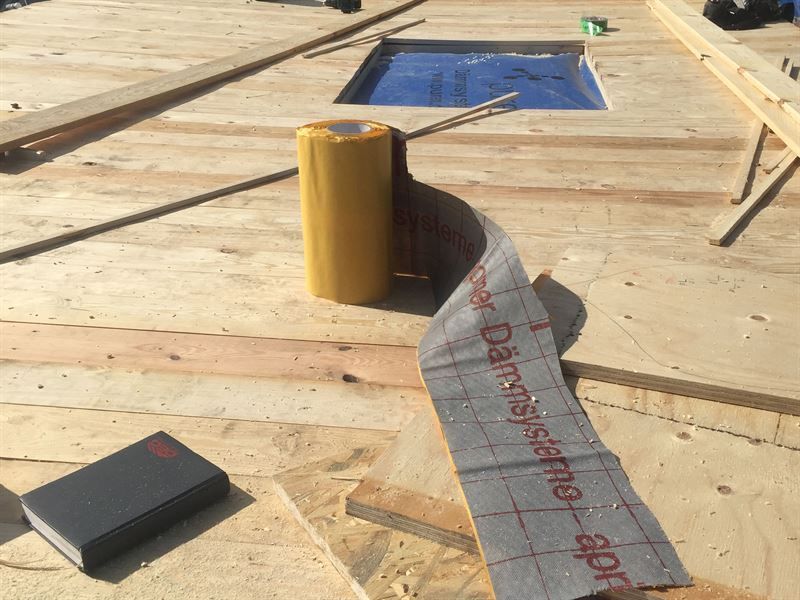 Auf einem Holzboden liegt eine Rolle Klebeband.