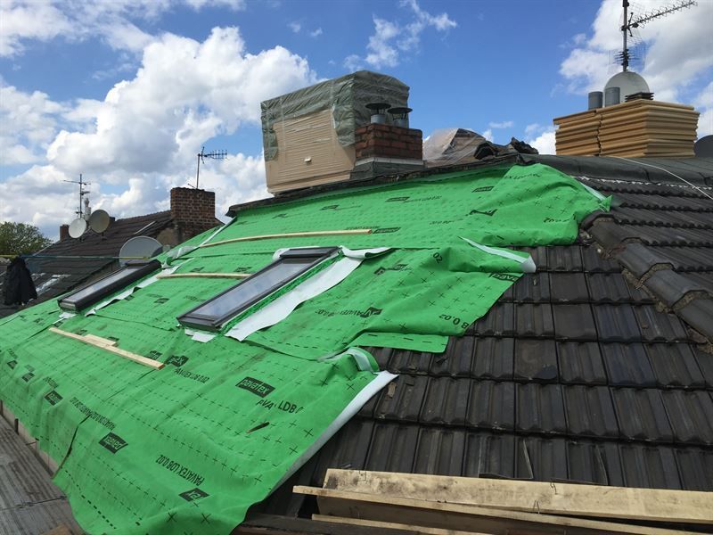 Eine grüne Plane bedeckt das Dach eines Gebäudes.