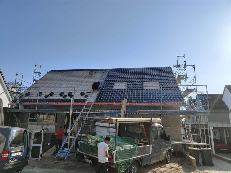 Ein Lieferwagen ist vor einem im Bau befindlichen Haus geparkt.