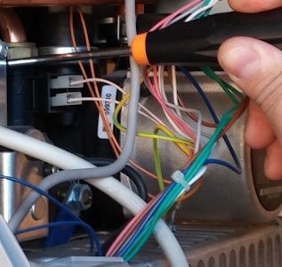 Un homme en salopette bleue installe un chauffe-eau solaire sur un toit sous un ciel bleu.