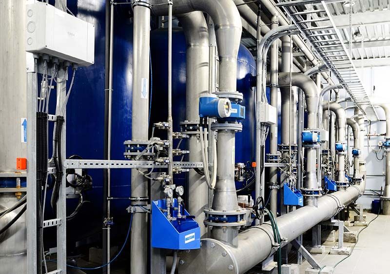 Équipement industriel avec réservoirs bleus et tuyaux argentés dans une installation.