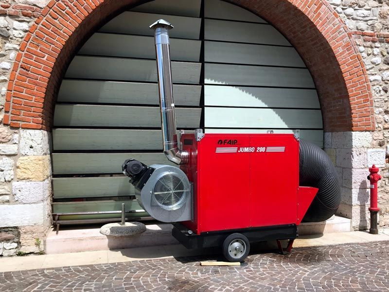 Unité de chauffage rouge avec une cheminée en métal contre une porte grise sous une arche en brique.