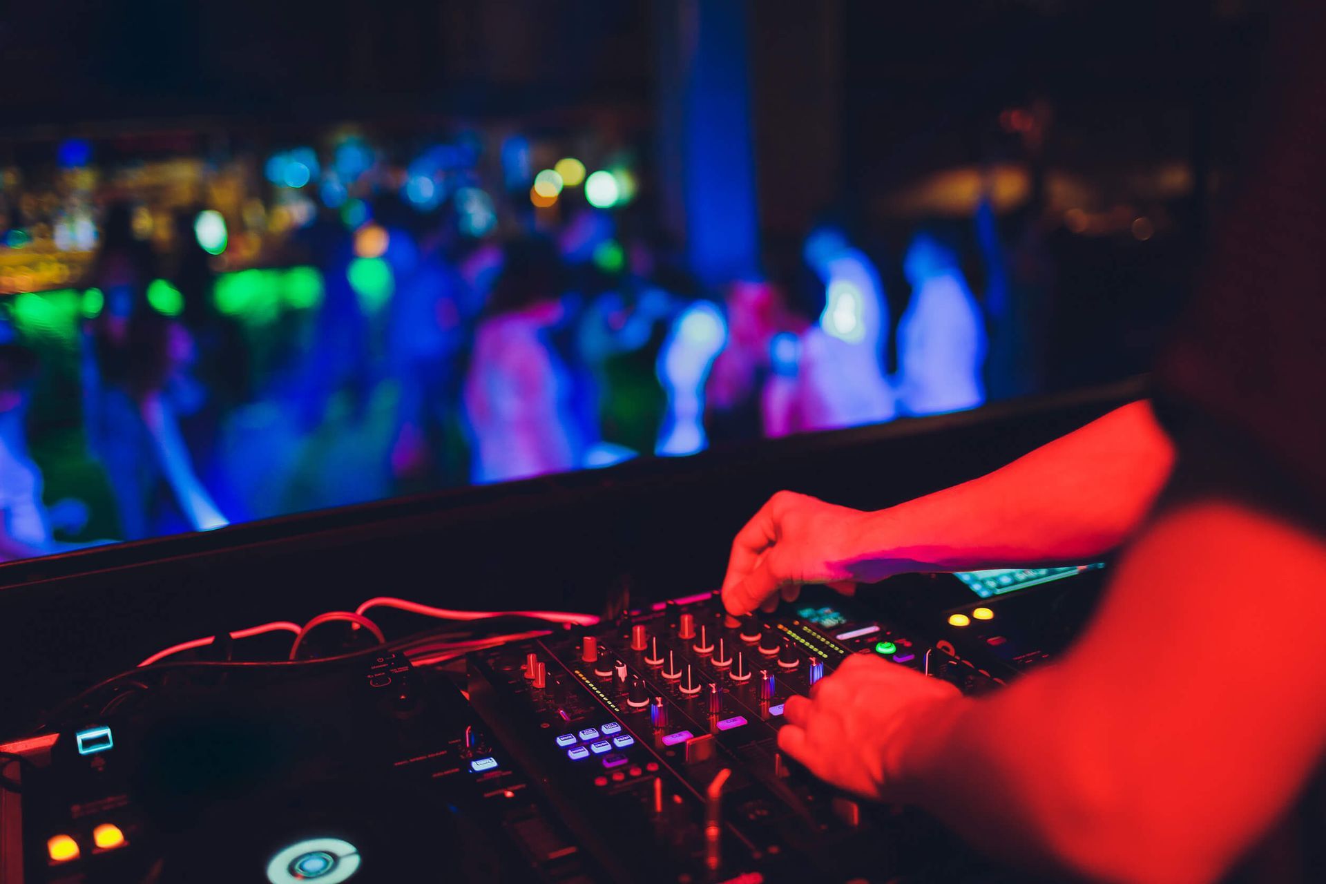 Un DJ está tocando música en una fiesta delante de una multitud.
