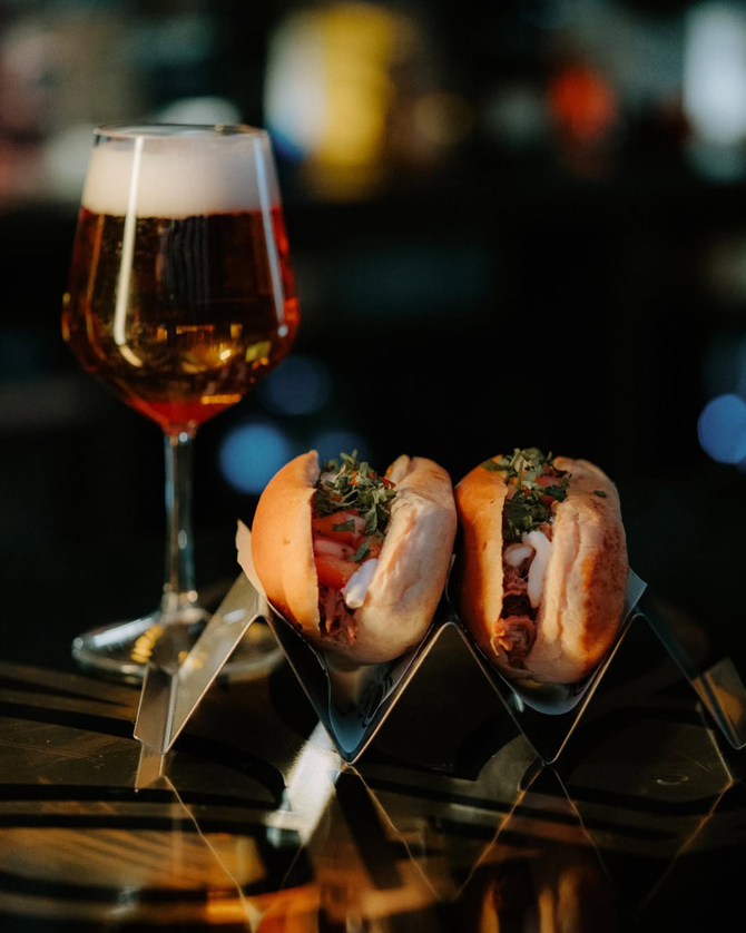Dos perritos calientes y un vaso de cerveza en una mesa