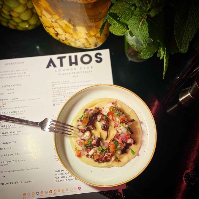 Un plato de comida con un tenedor junto a un menú del salón Athos.