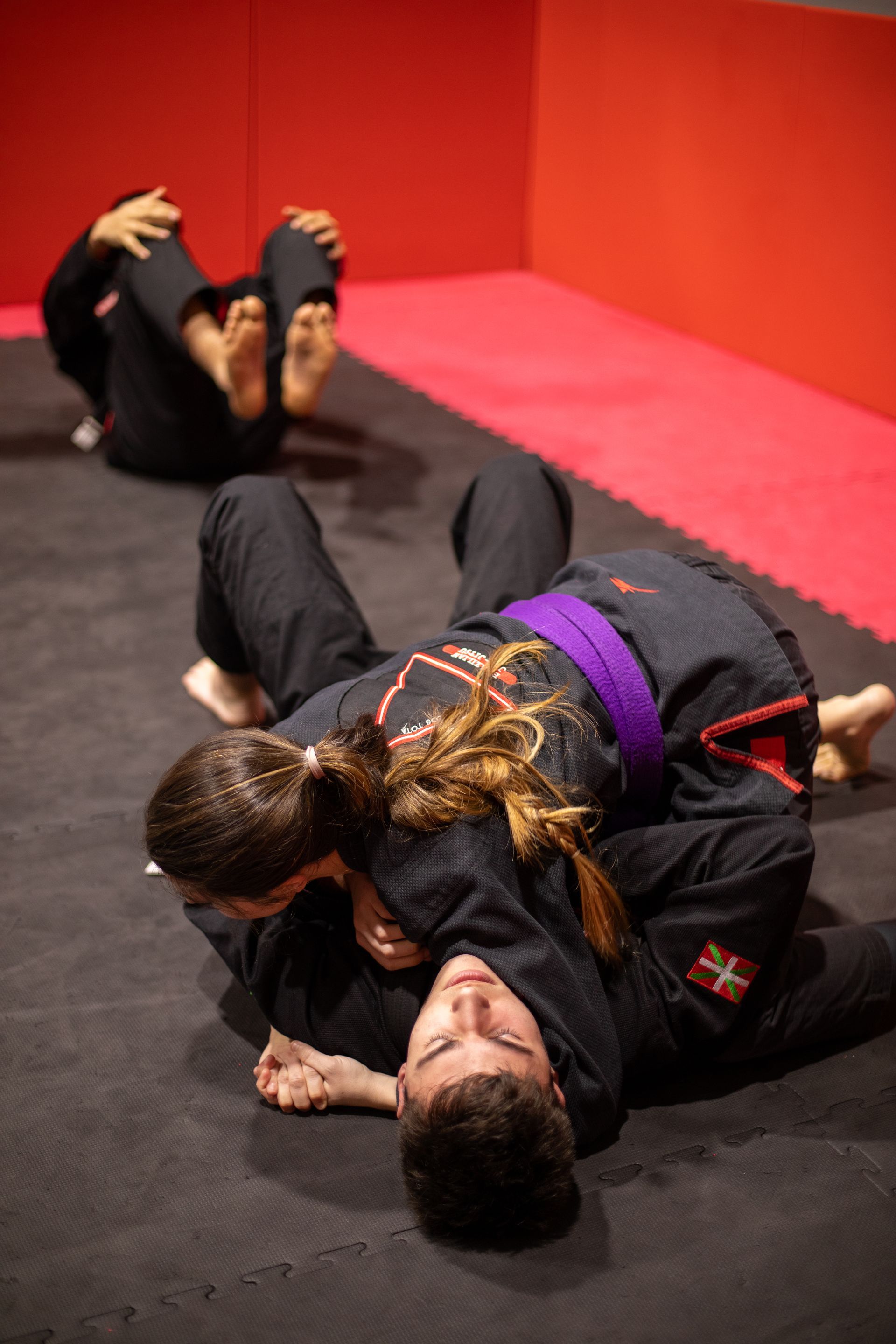 Un hombre y una mujer están luchando sobre una colchoneta en un gimnasio.