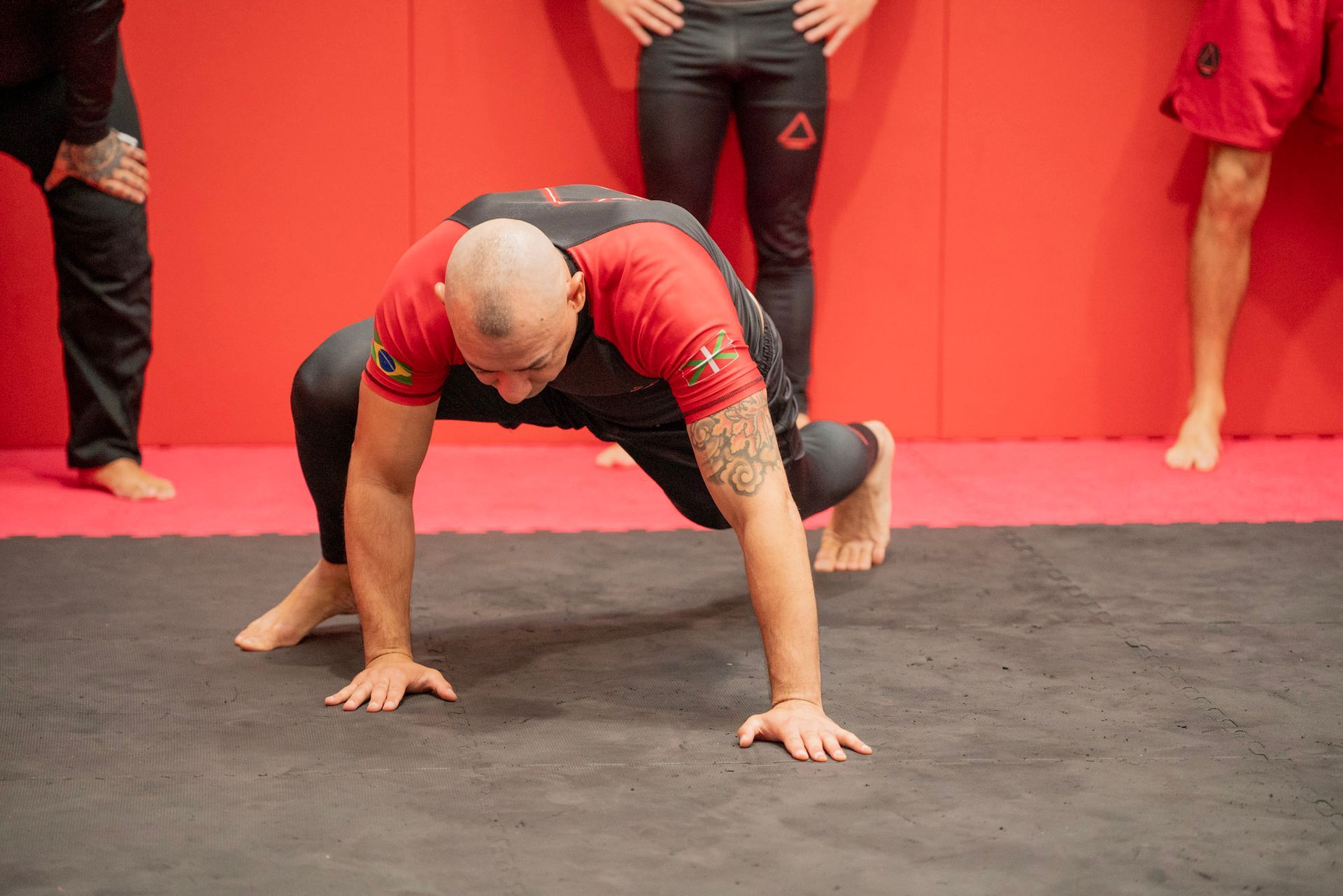 Un hombre está haciendo flexiones en el suelo en un gimnasio.