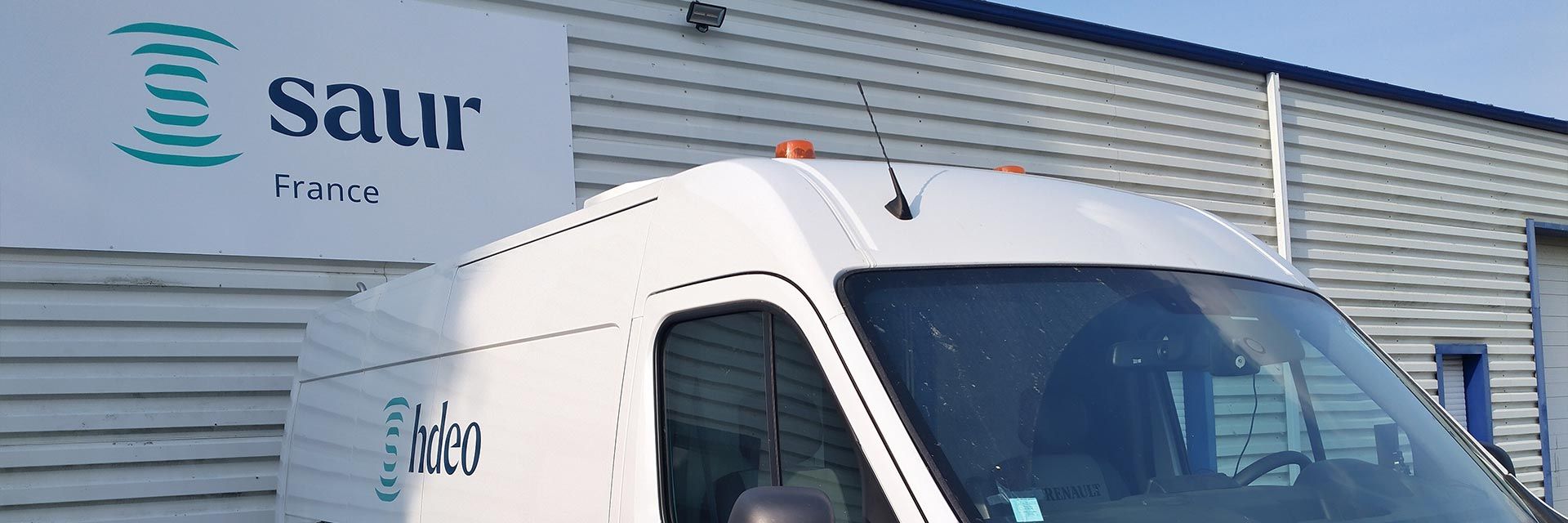 Photographie d'un camion et du logo SAUR au bâtiment