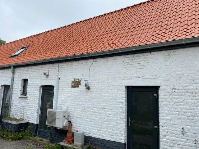 Maison blanche avec couverture ocre et portes noires