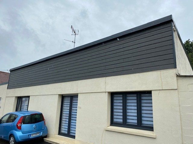 Bardage de maison beige et menuiseries extérieures noires