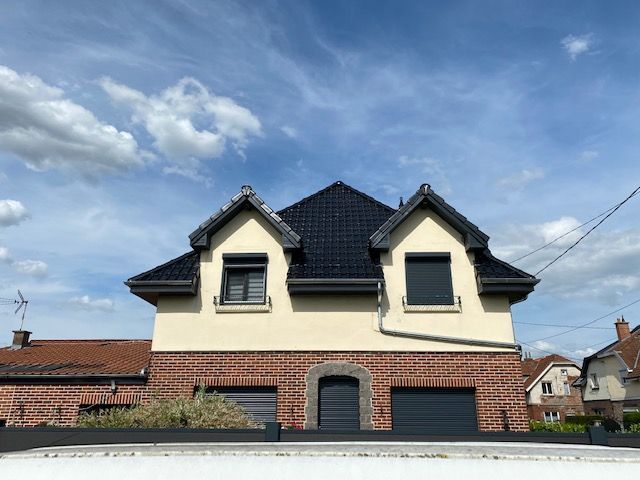 Maison en brique, revêtement en crépi et toiture noire