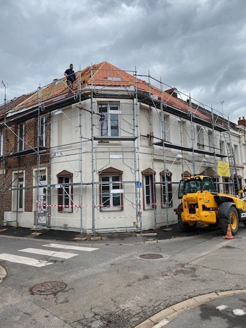 Échafaudage devant un immeuble blanc et rouge avec une nacelle