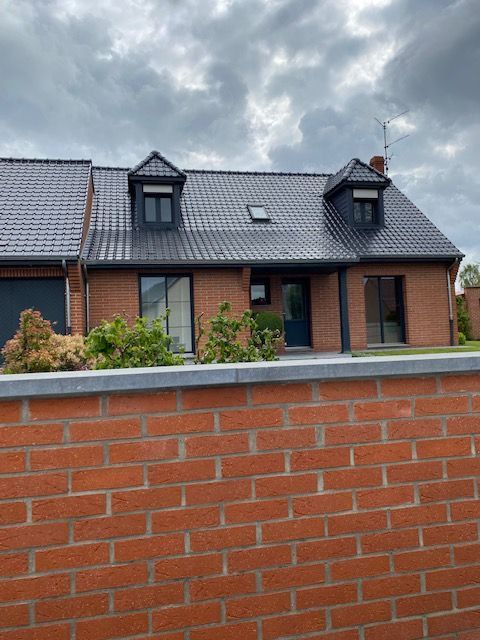 Muret rouge devant une maison avec couverture noire