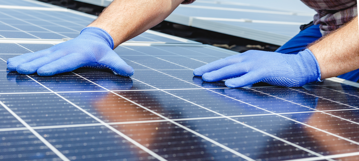 Professionnel avec des gants posant des panneaux photovoltaïques