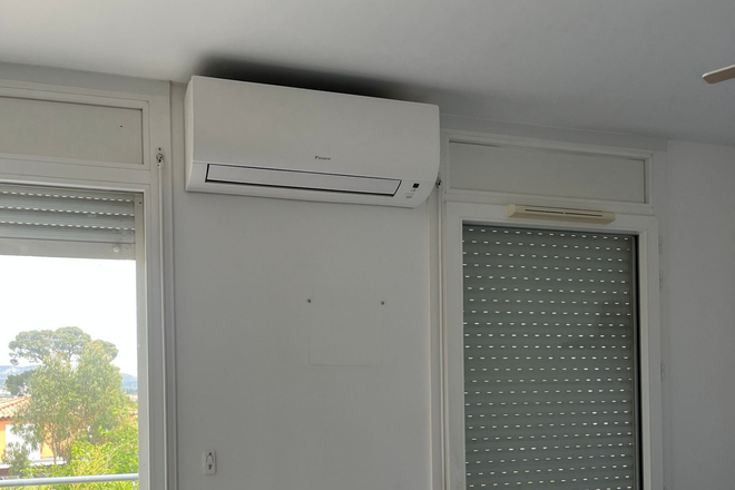 Climatiseur blanc fixé en hauteur à côté d'une porte