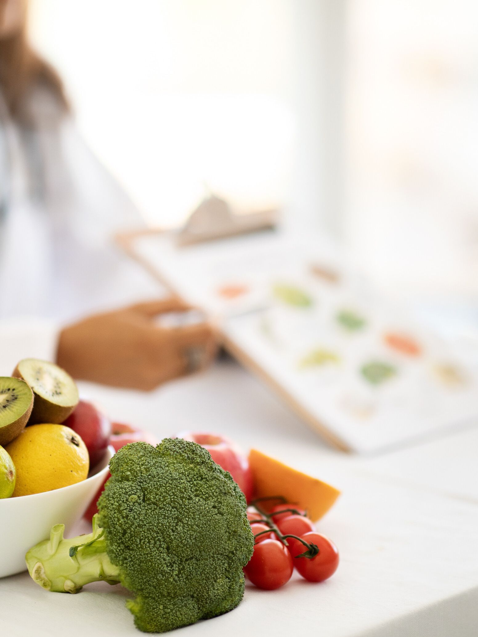 Una mujer está sentada en una mesa con un tazón de frutas y verduras.