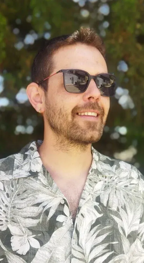 Un hombre que lleva gafas de sol y una camisa floreada está sonriendo.
