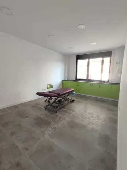 Una habitación con una mesa de masajes morada y armarios verdes.