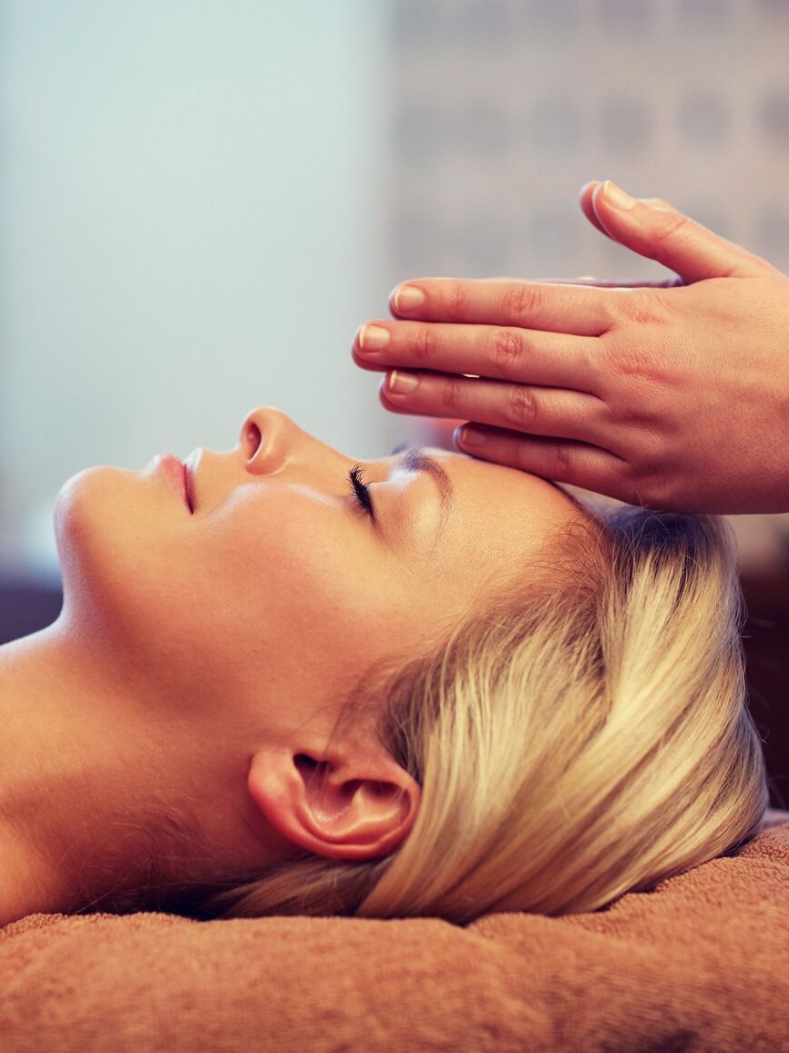 Una mujer está recibiendo un masaje de cabeza en un spa.