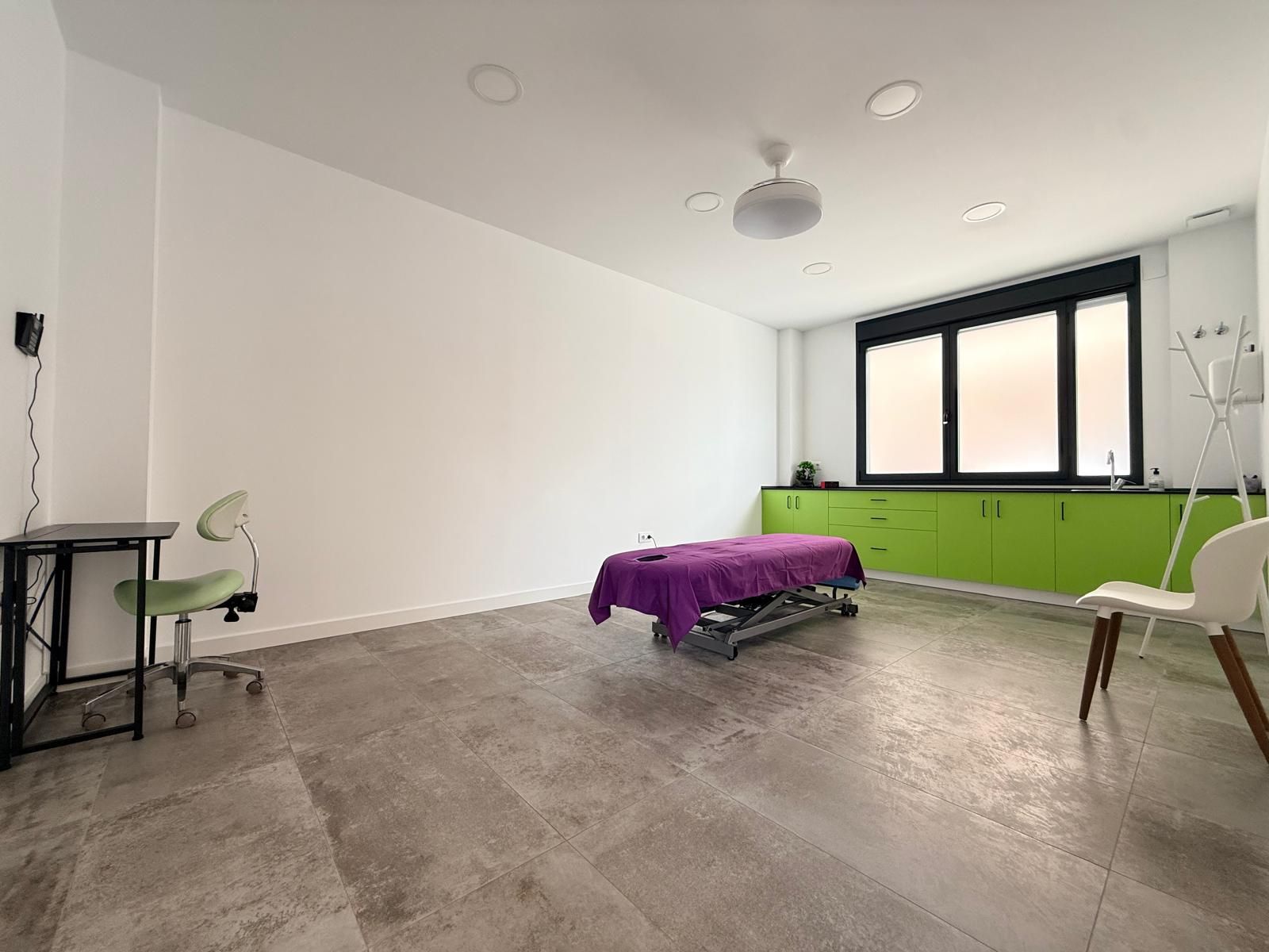 Habitación vacía con paredes blancas, suelo gris, armarios verdes y una mesa junto a la ventana.