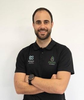 Un hombre con barba lleva un polo negro y un reloj.