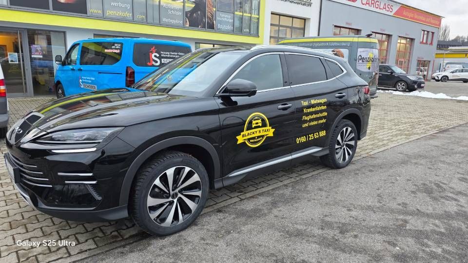 Schwarzer Geländewagen mit gelbem Logo, geparkt vor einem Gebäude.