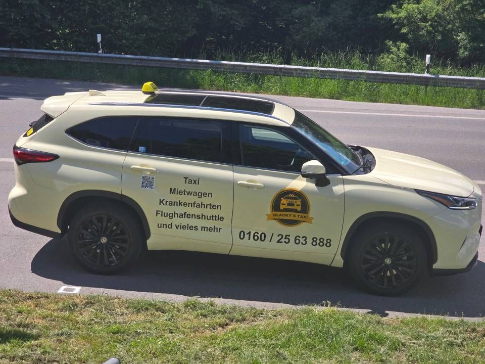 Gelber Geländewagen mit Taxi auf einer Straße, schwarze Felgen, Taxischild auf dem Dach, Werbung an der Seite.