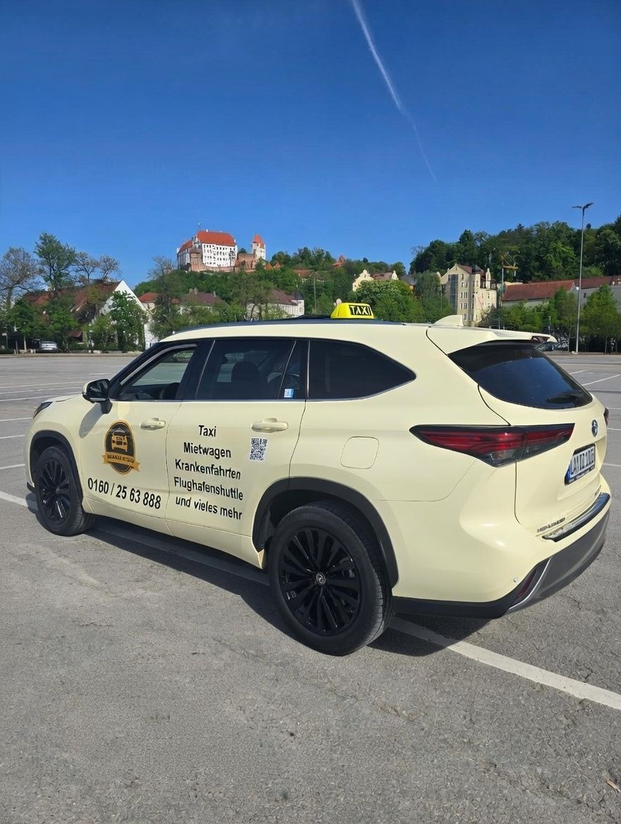 Ein gelber Geländewagen parkt an einem sonnigen Tag auf einem Parkplatz, im Hintergrund ist eine Burg zu sehen.