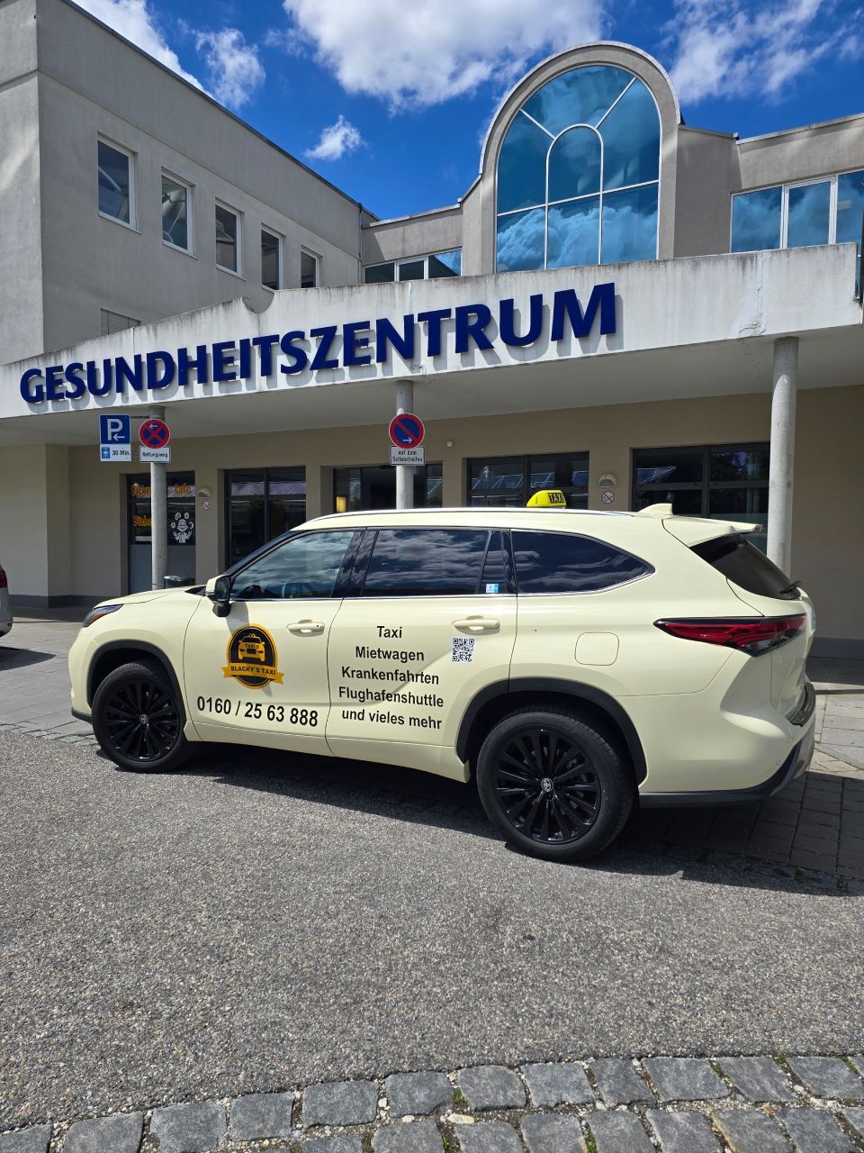 Ein gelbes Taxi parkt an einem sonnigen Tag vor einem „Gesundheitszentrum“.