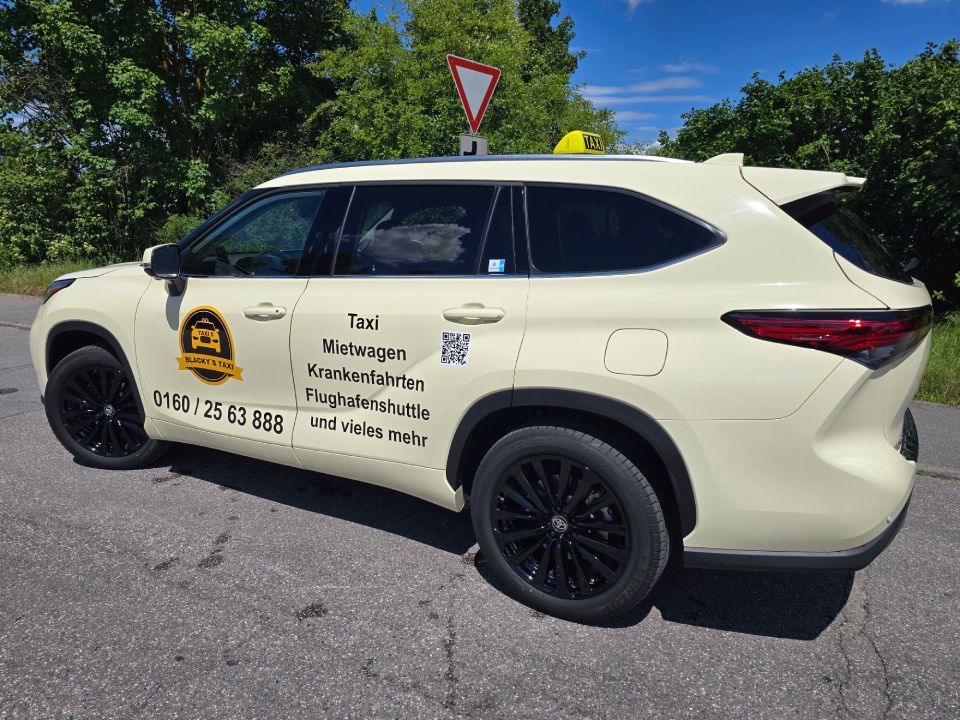 Ein gelber Geländewagen mit schwarzen Felgen parkt auf einer asphaltierten Straße vor einer von Bäumen gesäumten Straße.