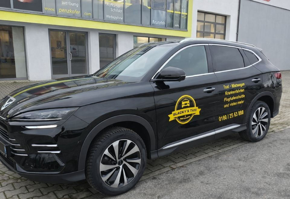 Schwarzer Geländewagen mit Firmenlogo parkt vor einem Gebäude.