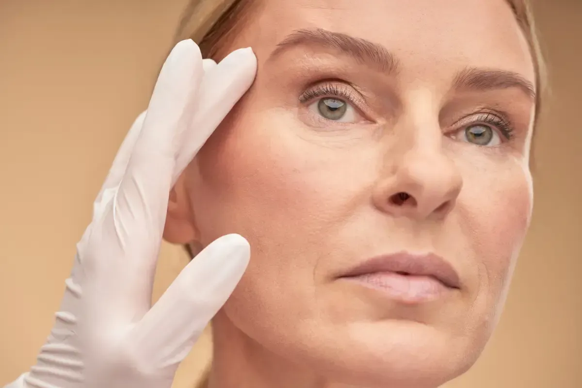 Una persona que recibe un tratamiento de fototerapia cosmética en el rostro mediante un dispositivo portátil.