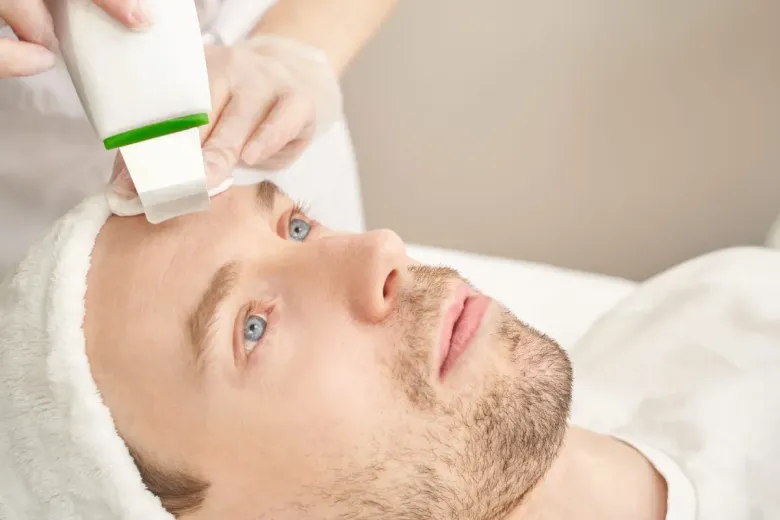 Una persona con mascarilla y guantes rosas utiliza una espátula ultrasónica manual 