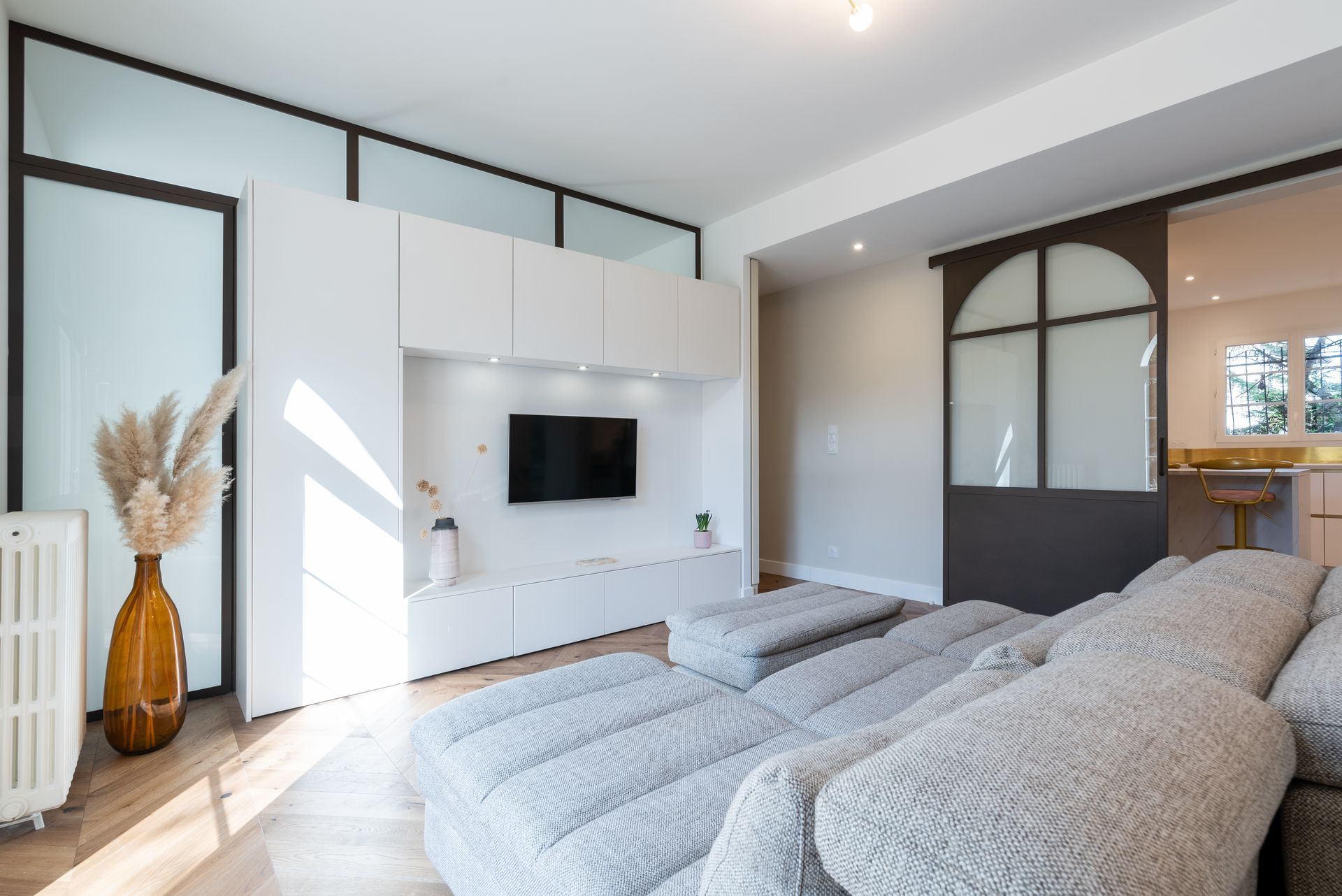 Salon avec un grand canapé central et télévision