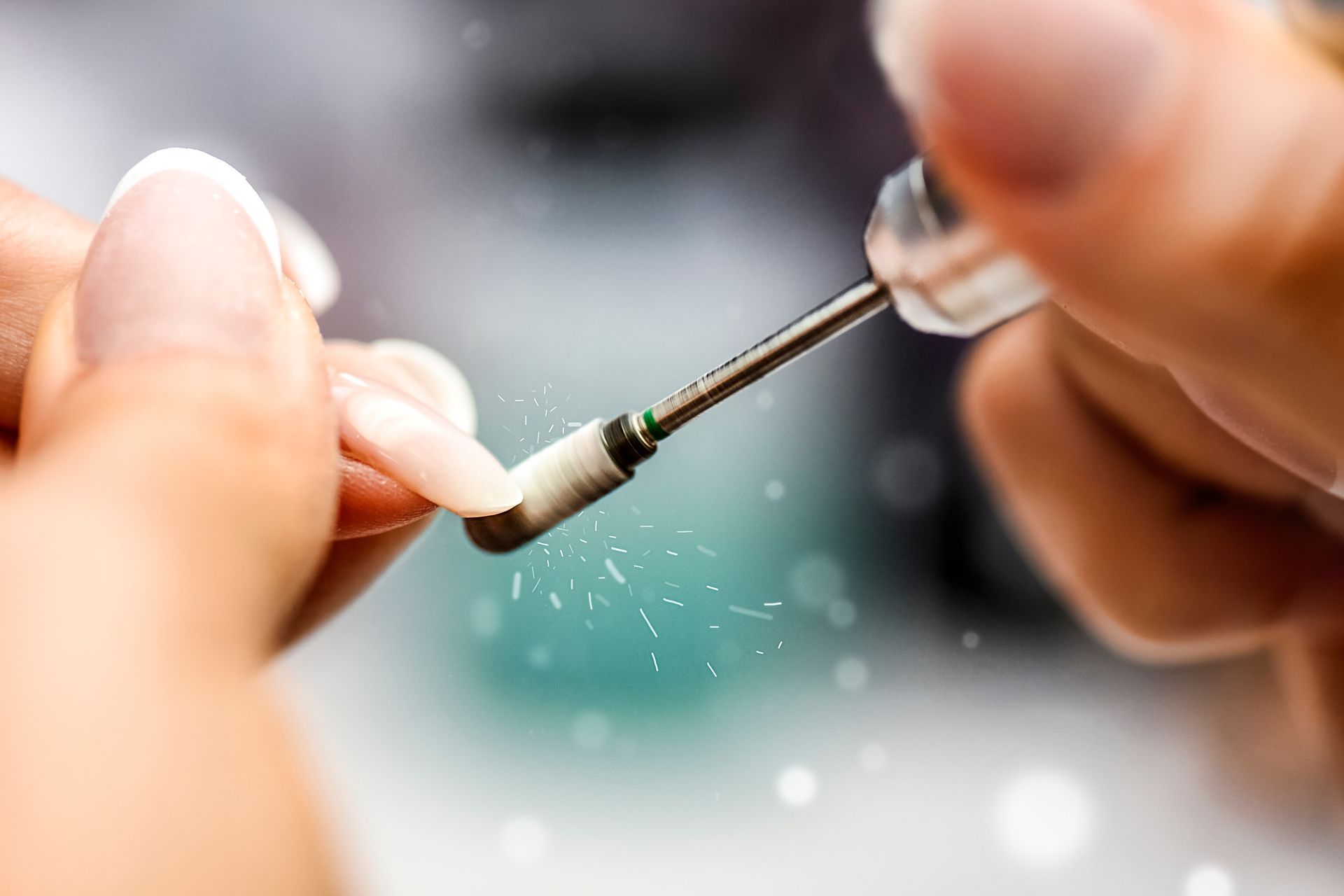 Manucure utilisant une perceuse à ongles pour façonner un ongle, étincelles volantes, gros plan.